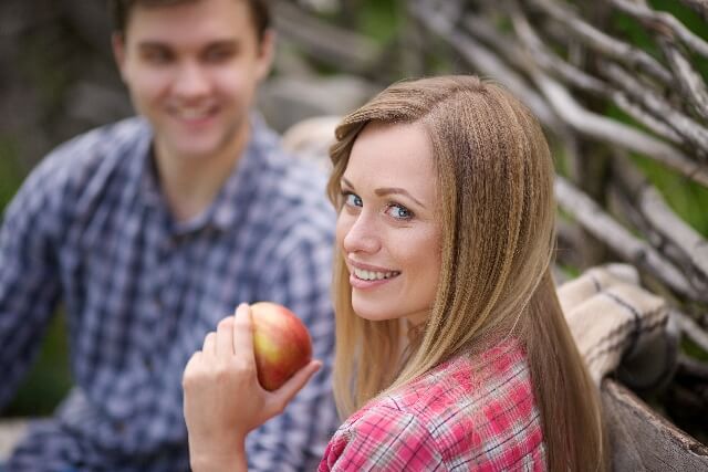 リンゴを持ち笑顔で振り向く女性