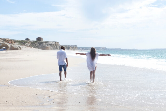海辺で水に濡れながら歩くカップル