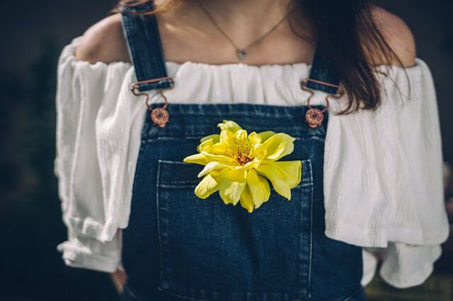 胸ポケットに黄色い花を入れて歩く女性