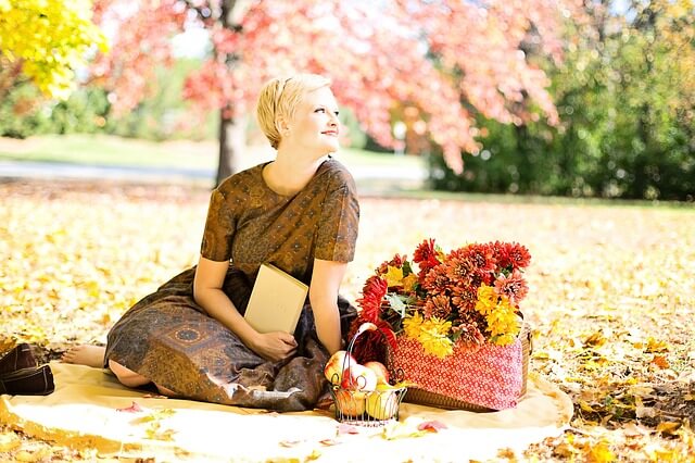 紅葉した木の下で本を読む女性