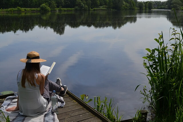 湖のほとりで本を読む女性