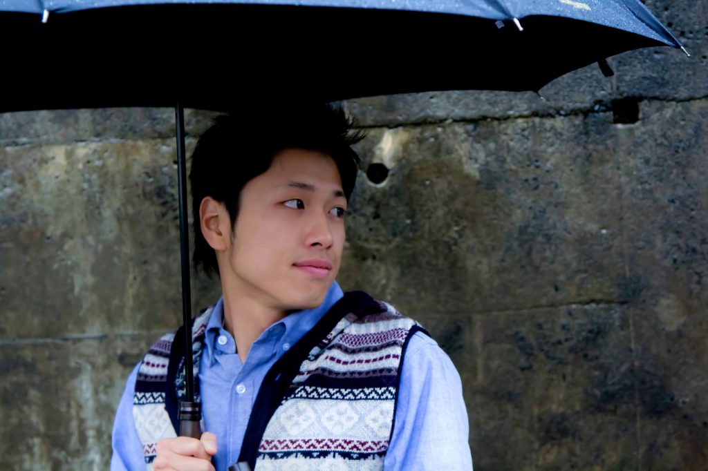 雨の日に傘をさしている男性