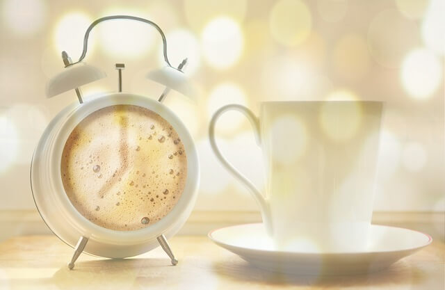 白い目覚まし時計とコーヒーカップ
