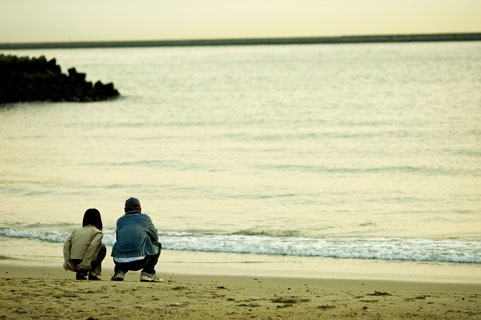 浜辺で座って話すカップル