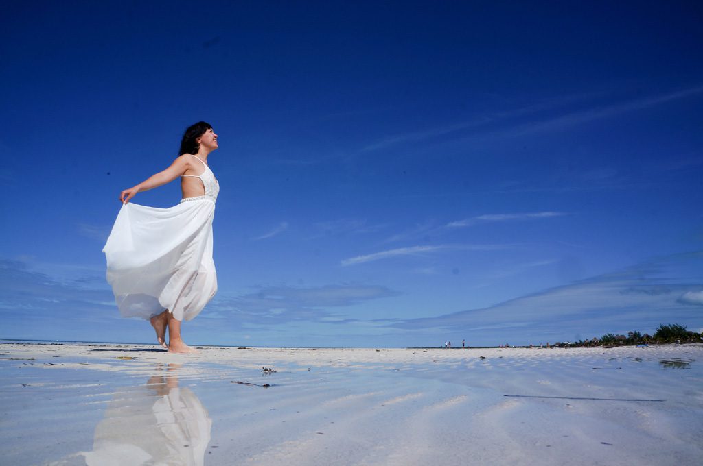 砂浜を笑顔で歩く女性