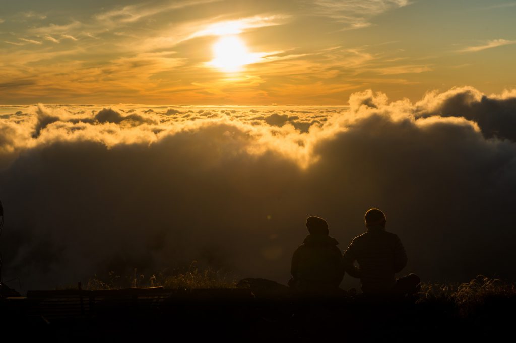 夕暮れの雲海の絶景に感動するカップル
